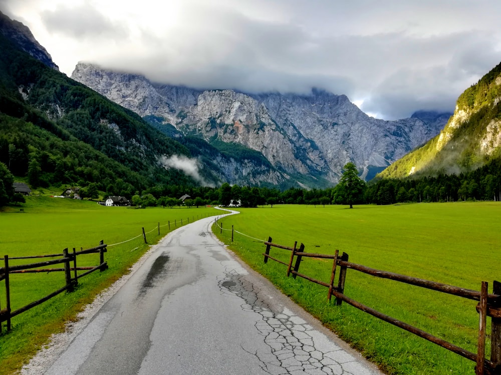 a road in the middle of a field with mountains in the background