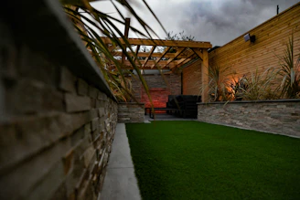 a backyard with a green lawn and a stone wall