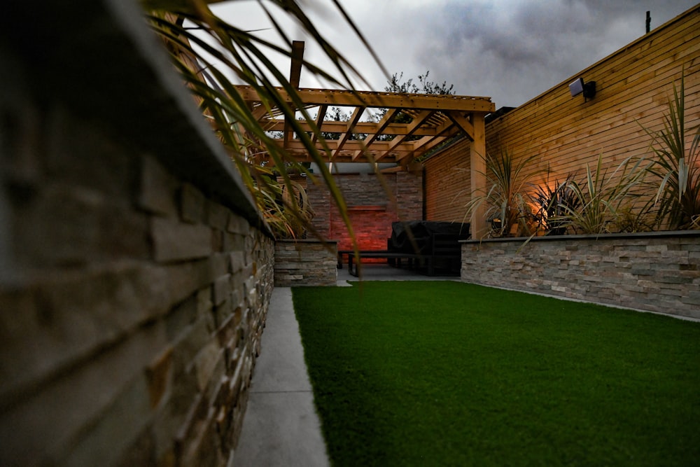 a backyard with a green lawn and a stone wall