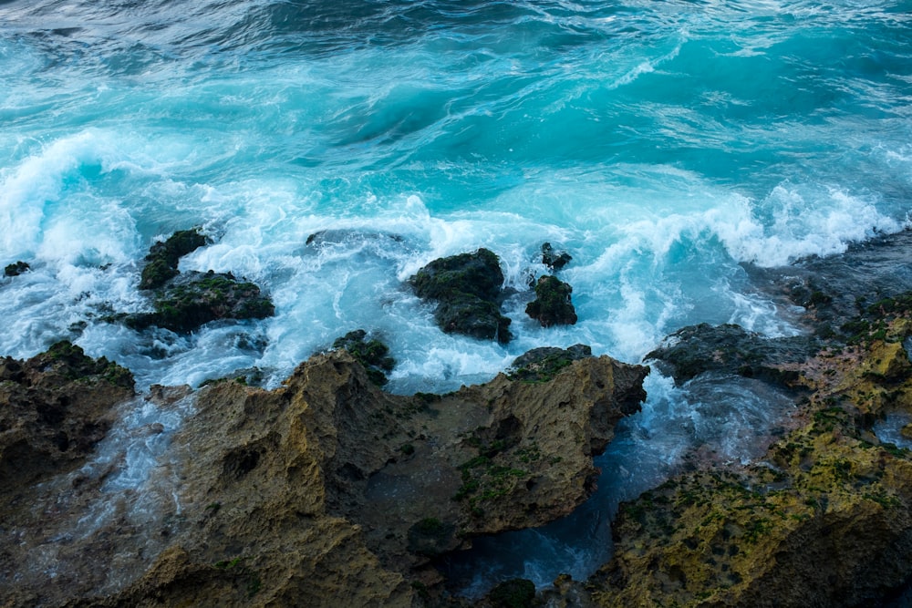 a rocky shore with blue water and foamy waves