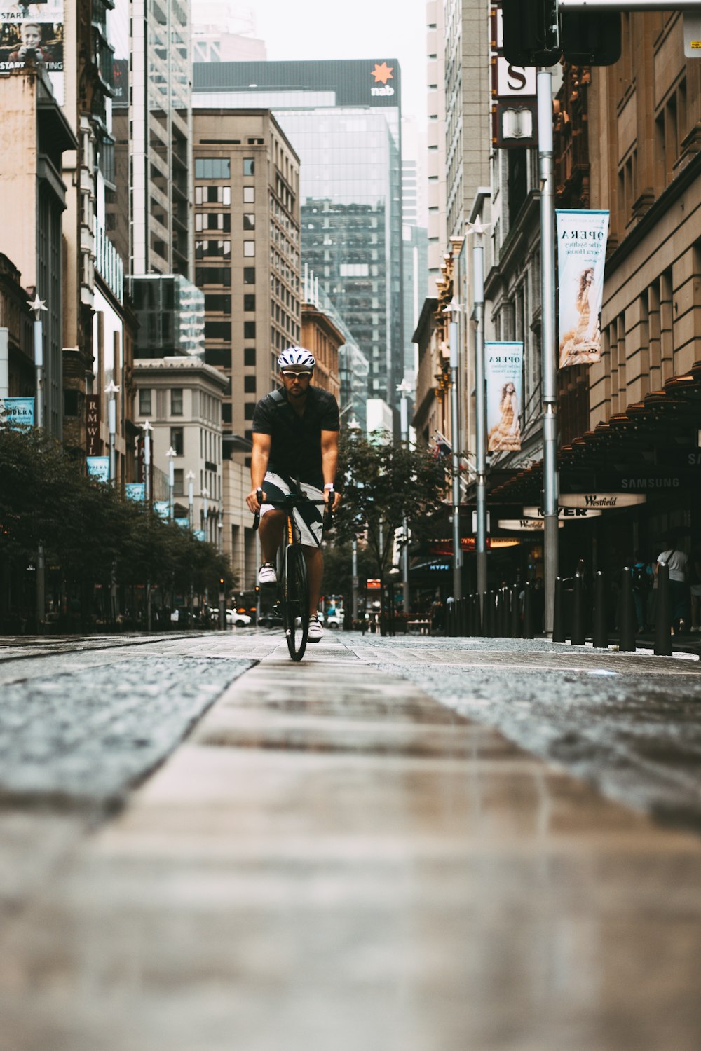 a man riding a bike down a street next to tall buildings