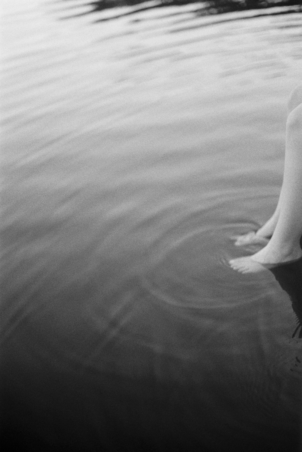 a black and white photo of a person's legs in the water
