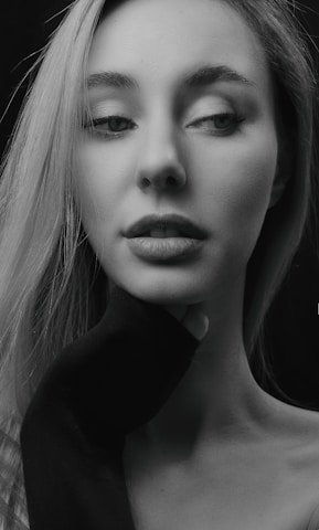 Black and white portrait of Debra Anne Cook with a thoughtful expression, minimalistic background.