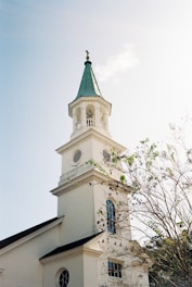 a white church with a green steeple and a clock