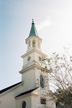 a white church with a green steeple and a clock