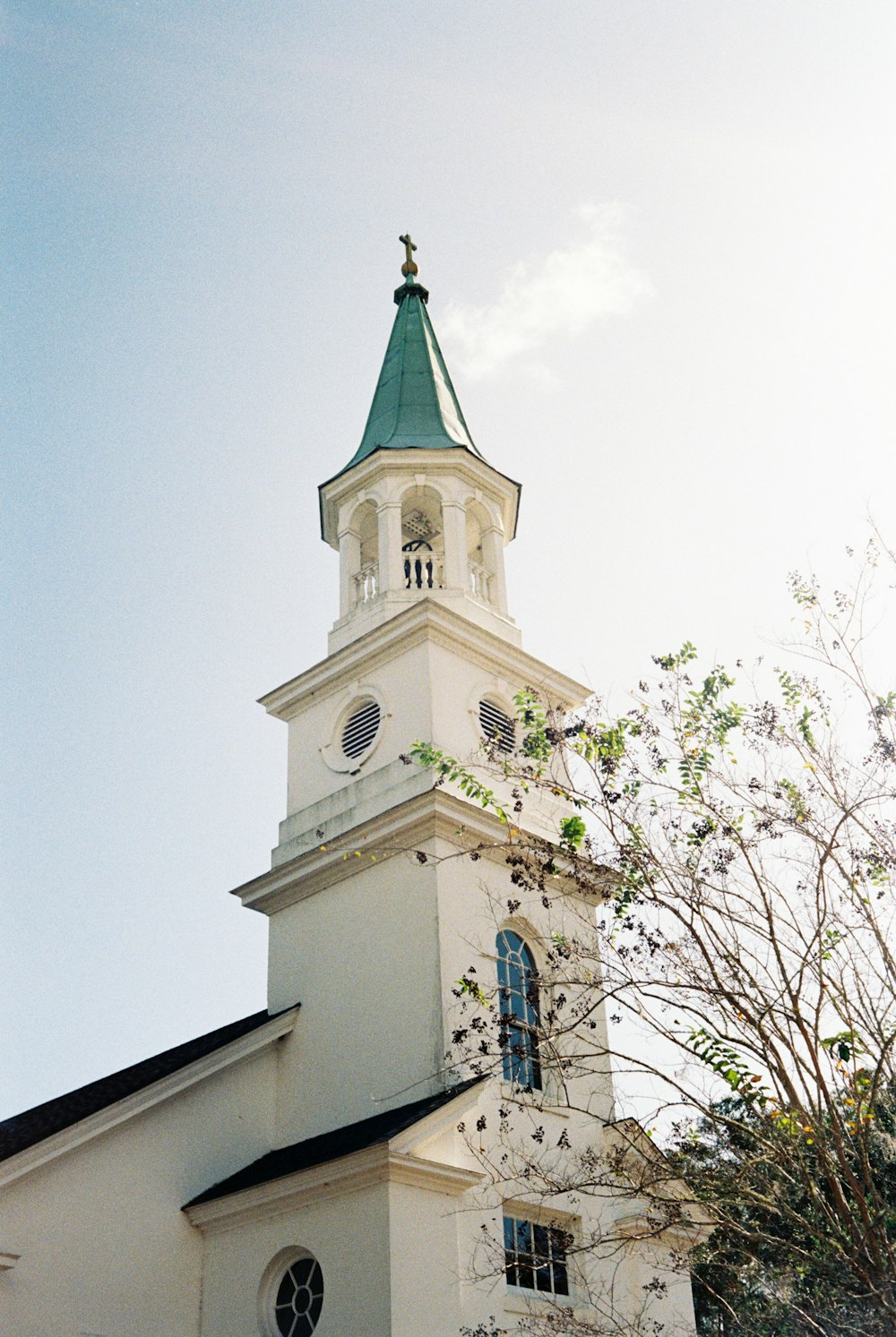 a white church with a green steeple and a clock