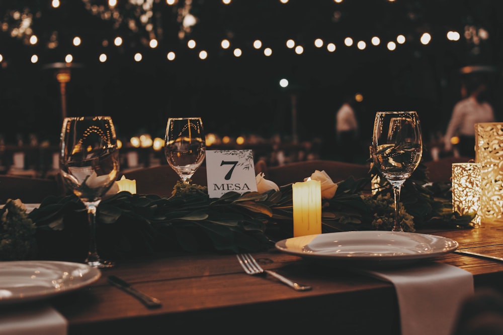 a table set for a formal dinner with candles and place settings