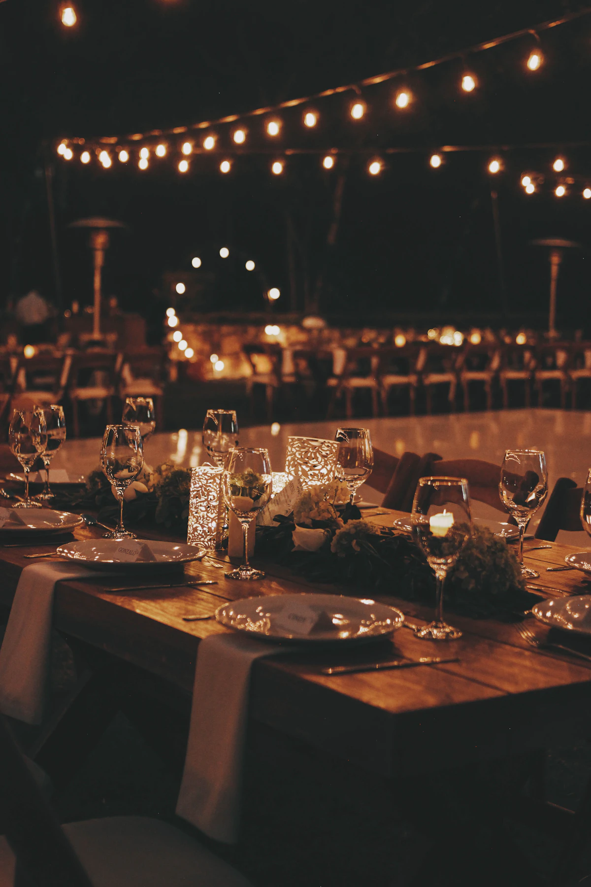 Festoon lights strung above long tables in an outdoor courtyard
