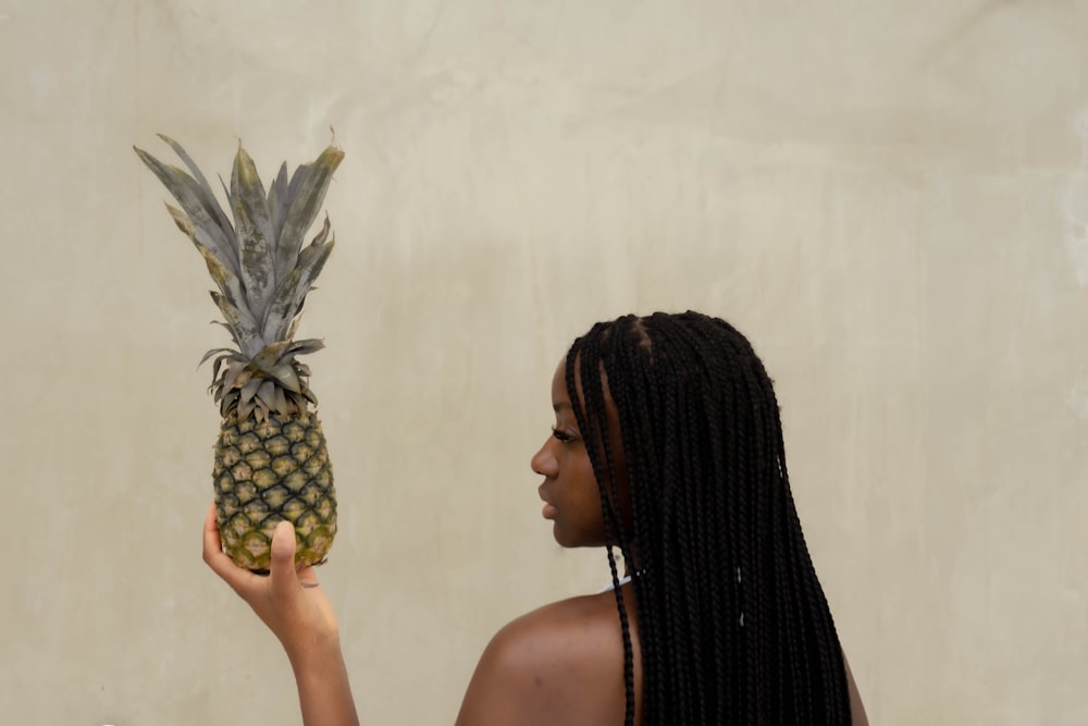 a woman holding a pineapple in front of her face