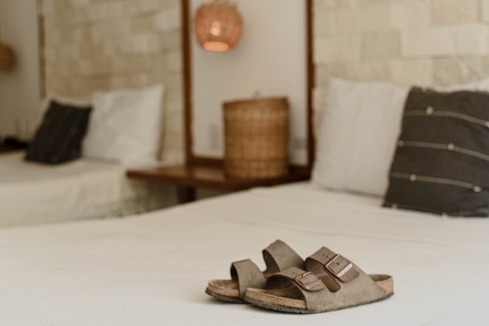 a pair of sandals sitting on top of a bed
