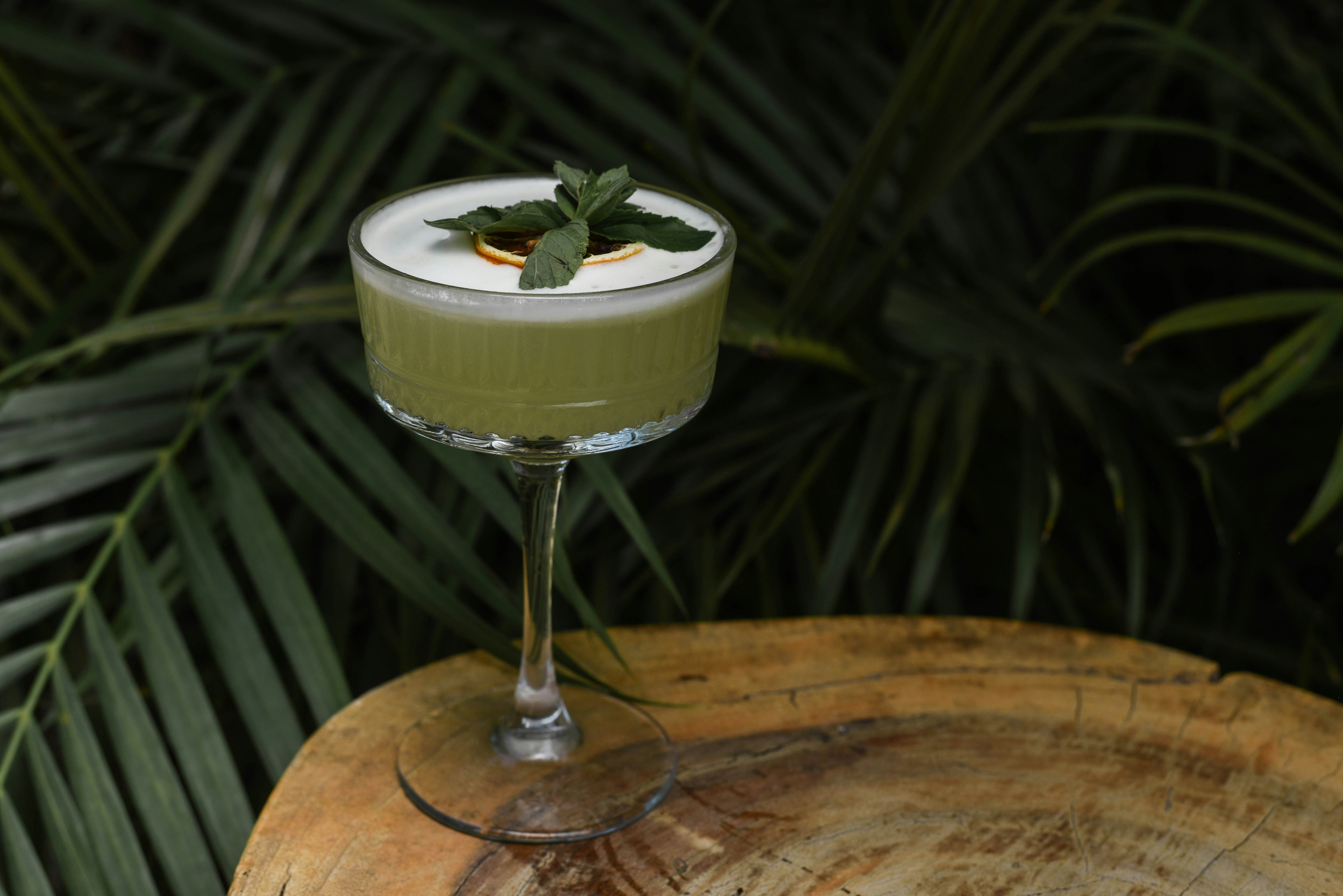 a green drink with a mint garnish in a glass, 