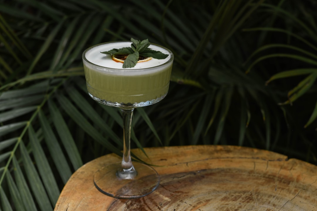 a green drink with a mint garnish in a glass,