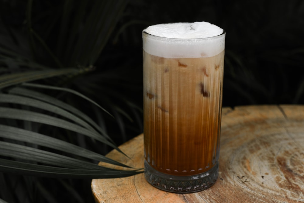 a tall glass filled with liquid sitting on top of a wooden table