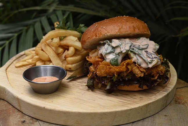 The new hot chicken sandwich served with a side of golden fries on a rustic wooden table.