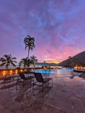 A serene backyard pool area with comfortable lounge chairs and soft lighting at dusk.