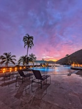 Outdoor pool area with stylish loungers and ambient lighting at dusk.