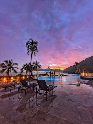 A beautifully remodeled pool and patio area with sleek decking and elegant outdoor lighting at sunset.