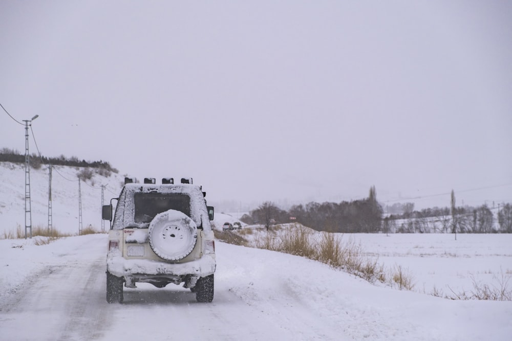 a white truck driving down a snow covered road