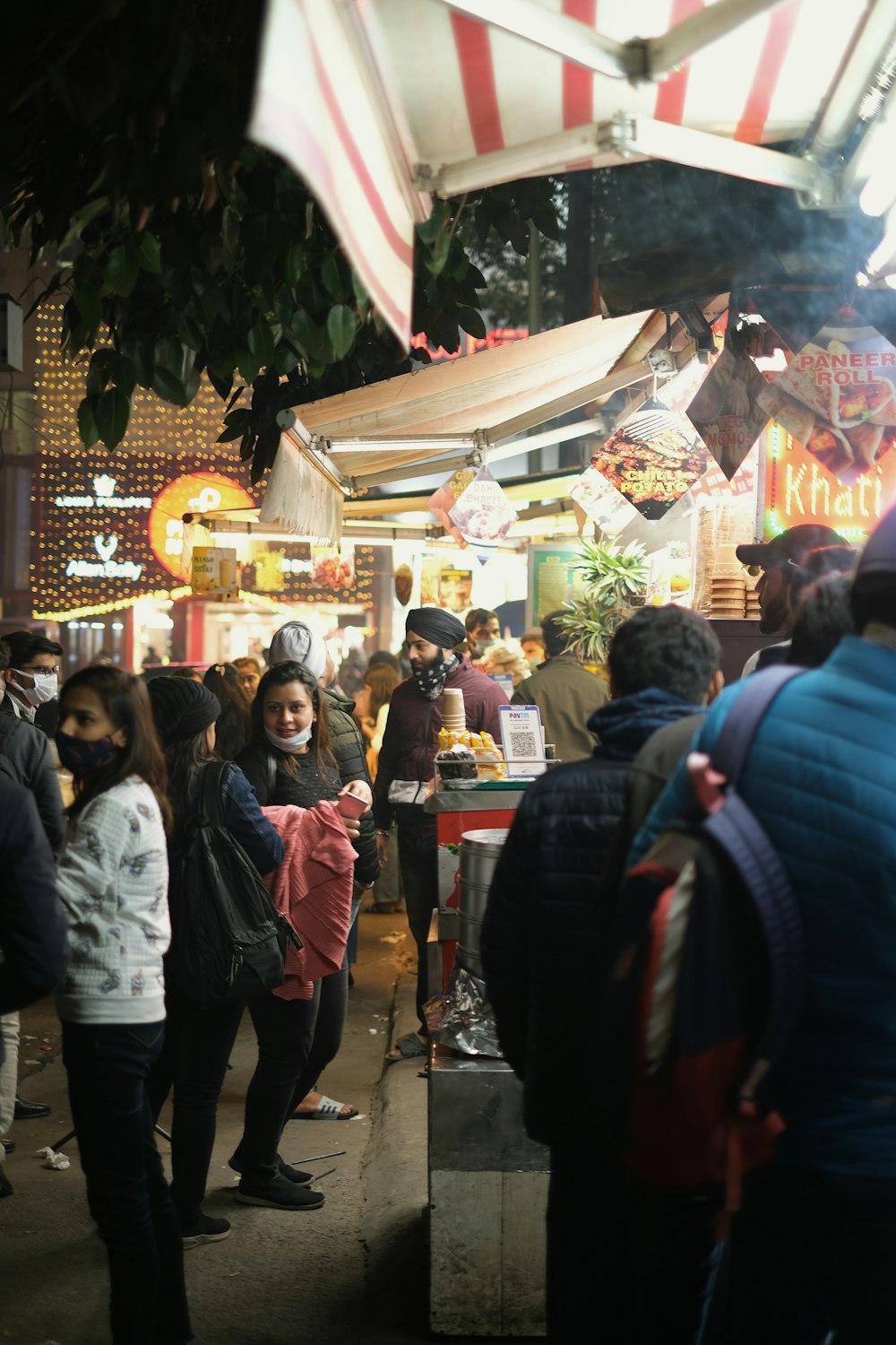 a crowd of people standing around a food stand