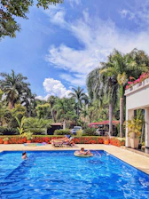Family relaxing by a sparkling hotel pool surrounded by tropical flowers.