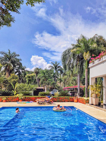 Family enjoying the pool area surrounded by tropical plants at a vacation rental.