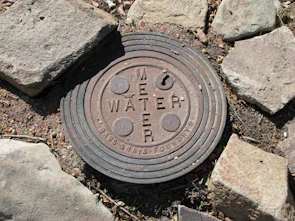 a manhole cover in the ground surrounded by rocks