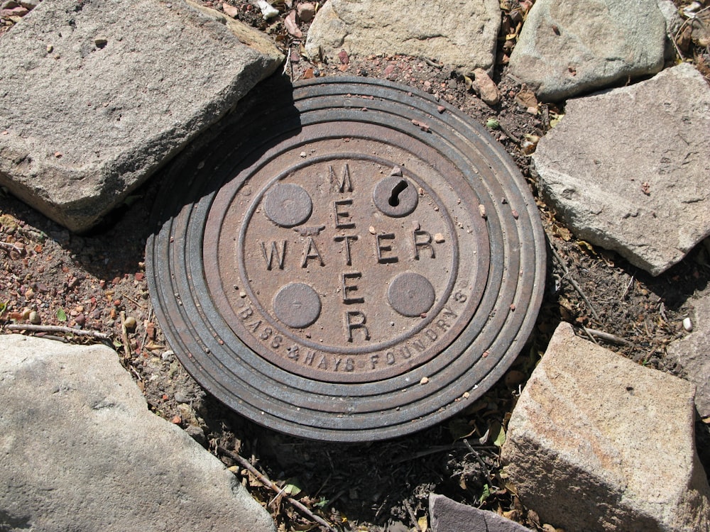 a manhole cover in the ground surrounded by rocks