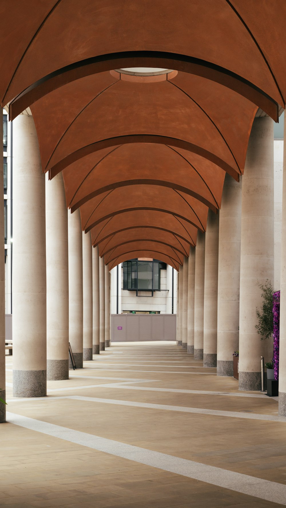 a long hallway with columns and a clock on the wall