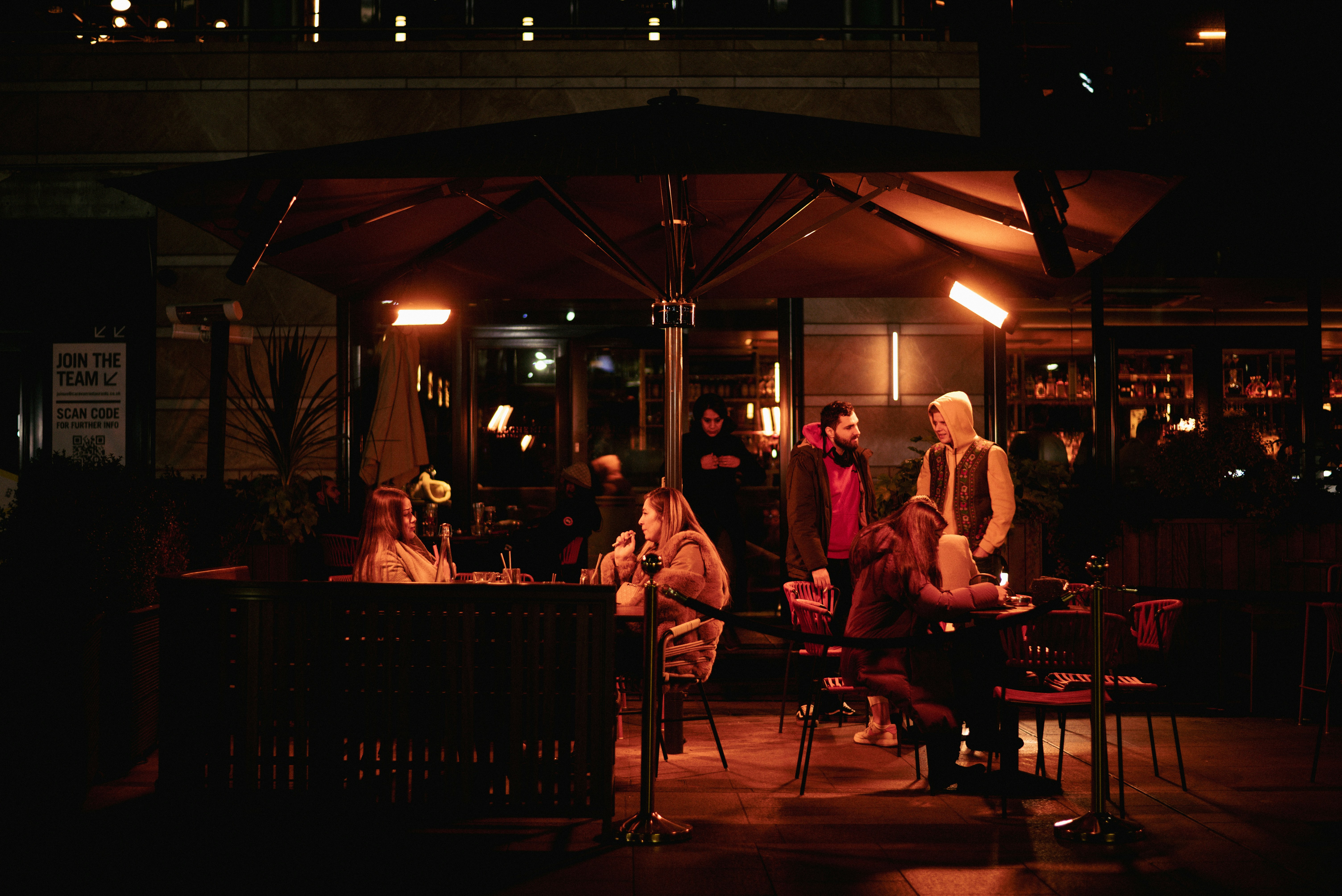 Eine Gruppe von Menschen sitzt an einem Tisch unter einem Sonnenschirm