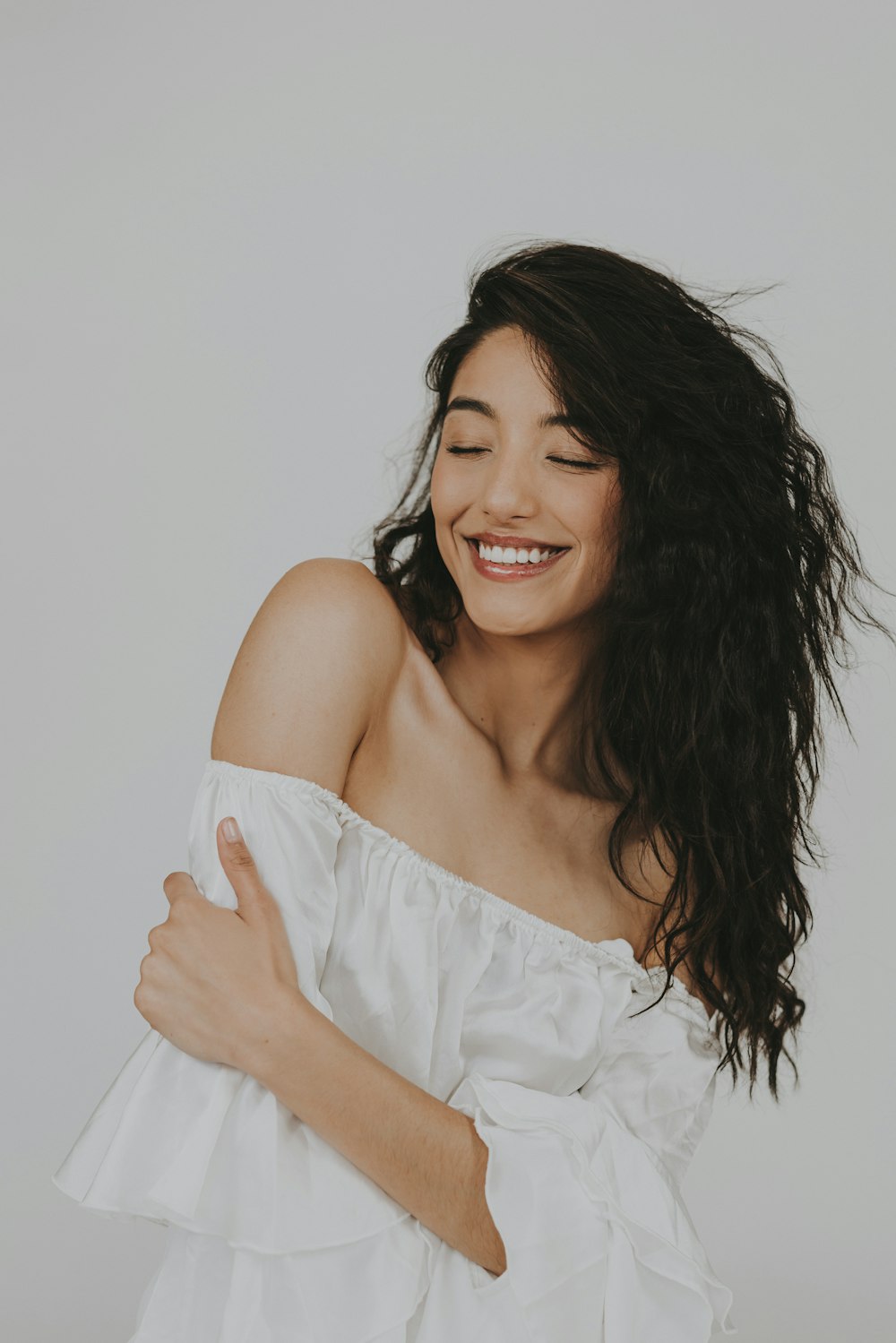 a woman with long hair smiling and wearing a white top