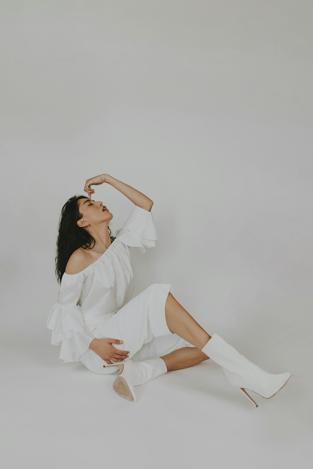 a woman sitting on the floor in white clothing