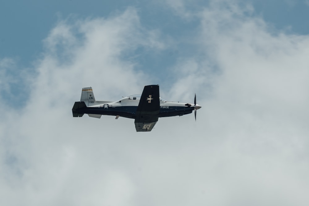 a small airplane flying through a cloudy blue sky