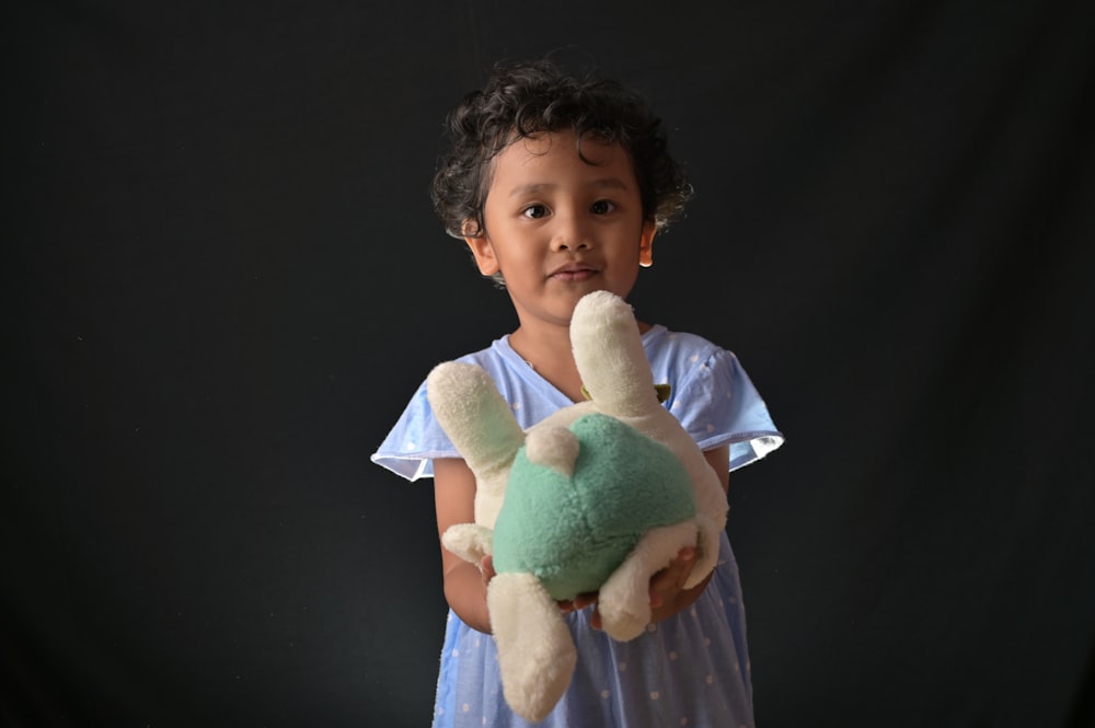 a little girl holding a stuffed animal in her hands