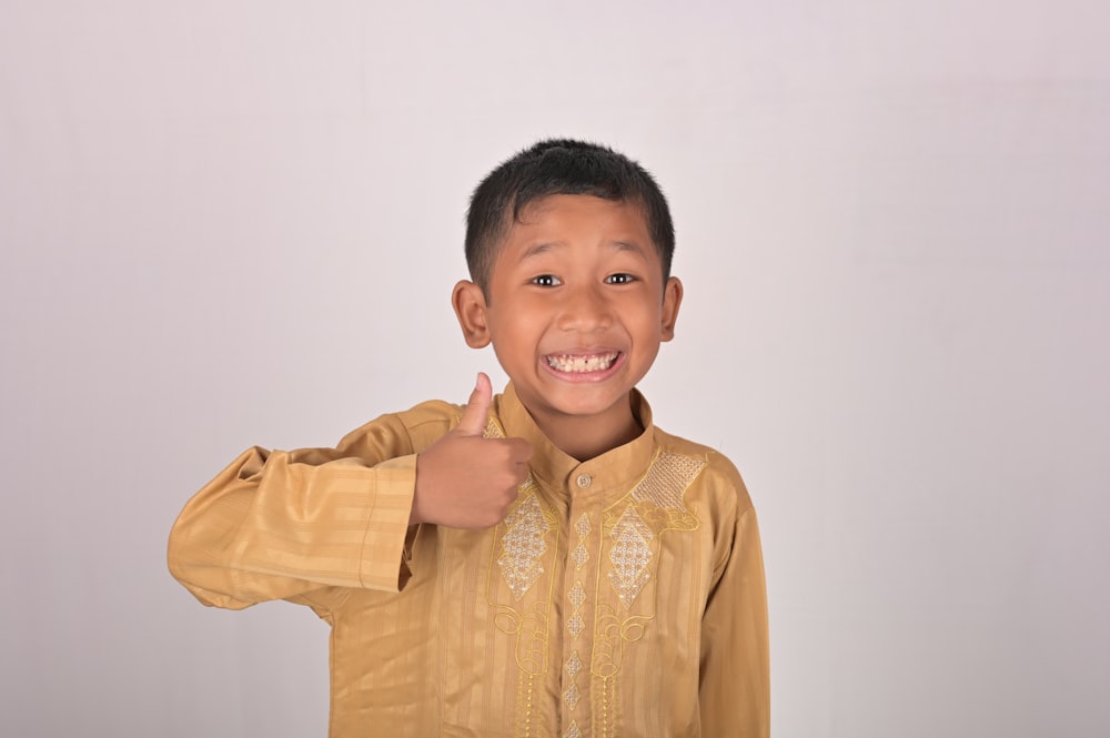 a young boy giving a thumbs up sign