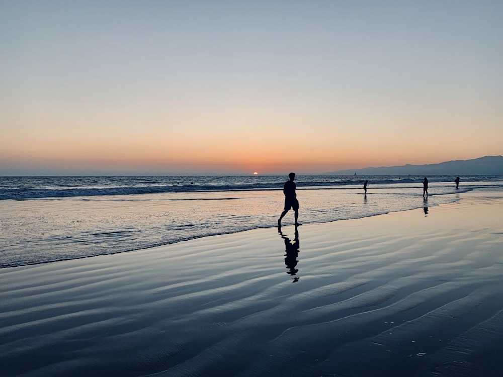 a group of people standing on top of a beach next to the ocean