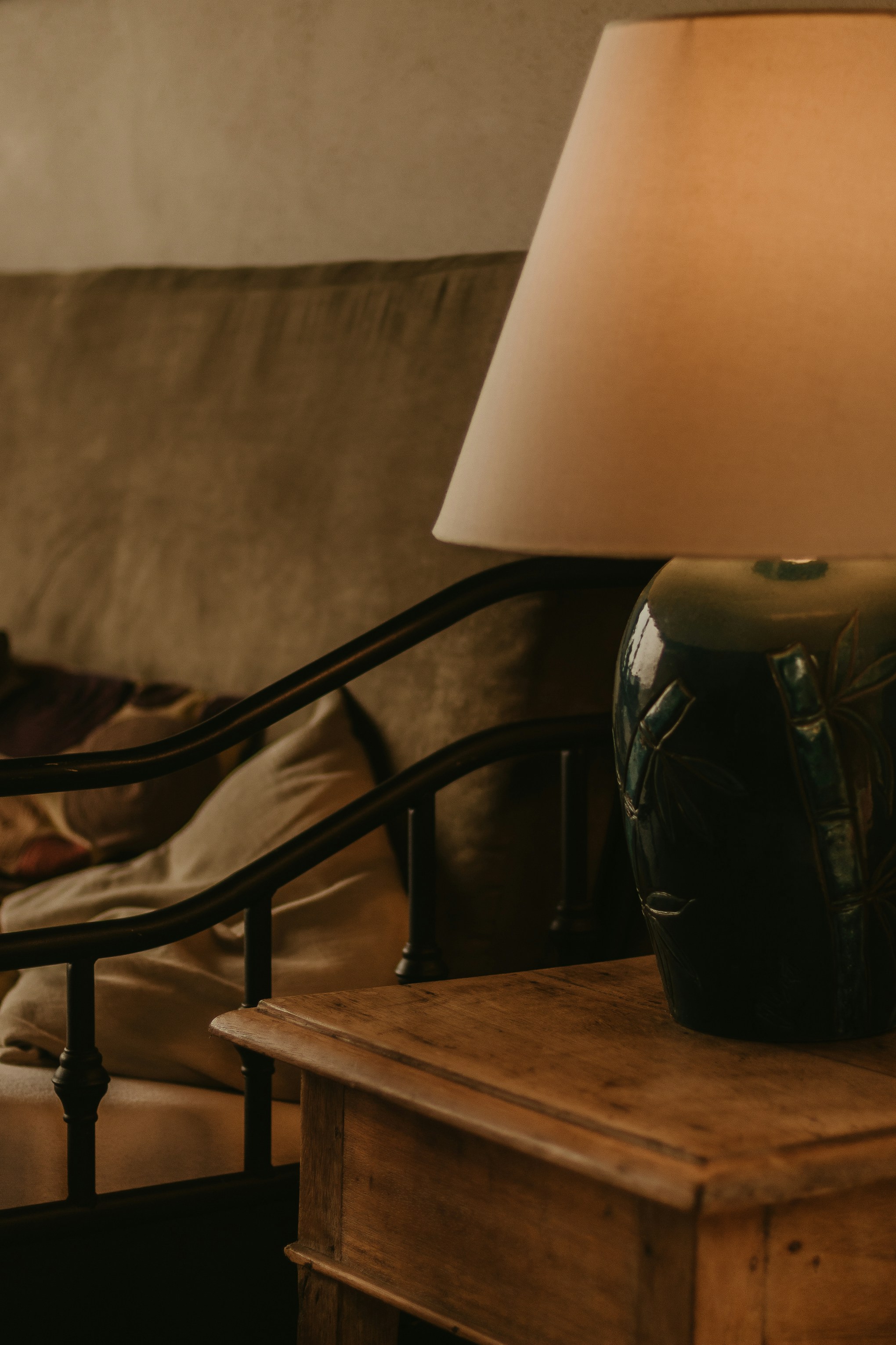 Designer twisted iron table lamp with cream linen shade on a dark wooden side table in a study