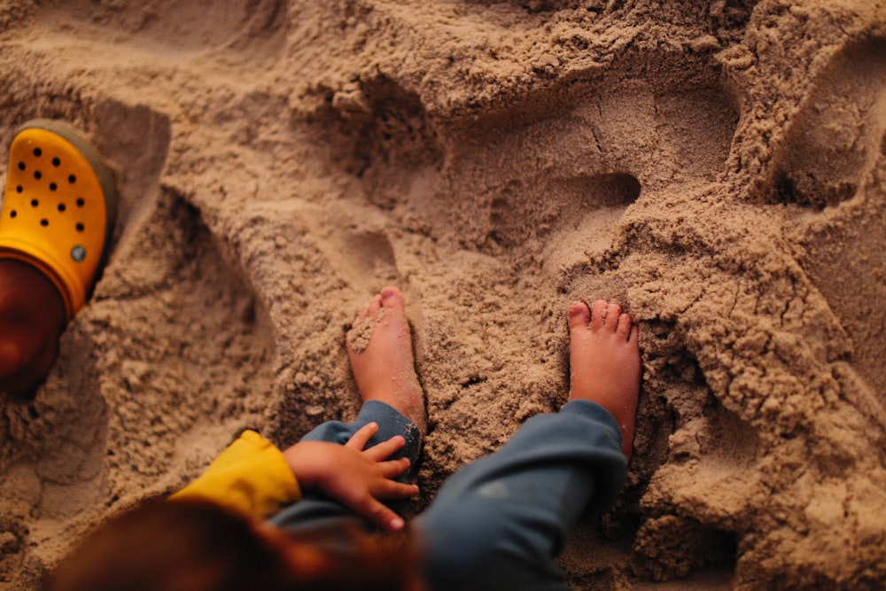 a child's feet sticking out of the sand