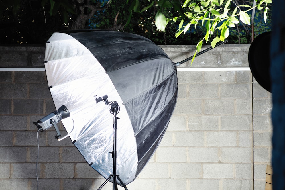 a white and black umbrella sitting in front of a brick wall