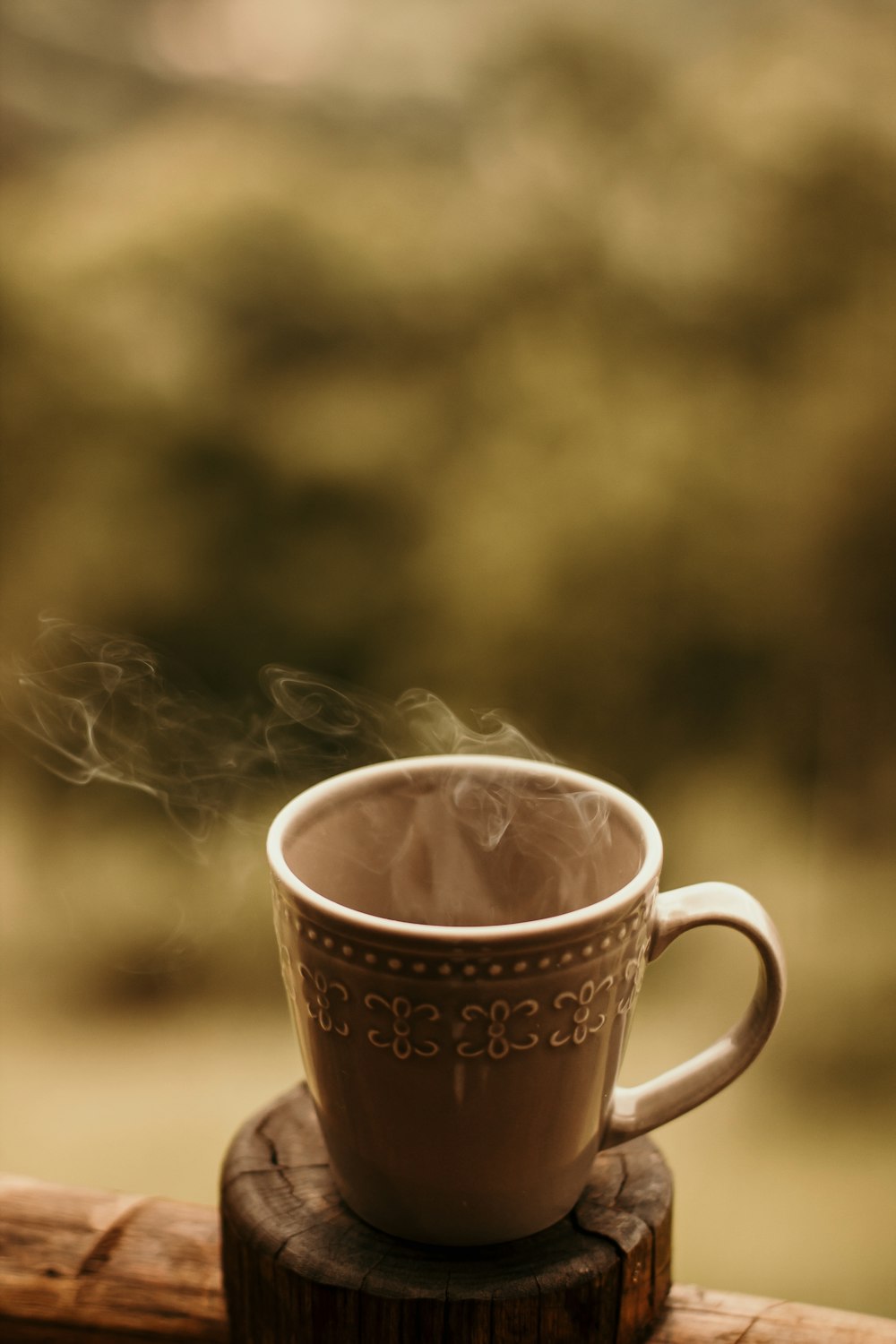 a steaming cup of coffee sitting on top of a wooden table