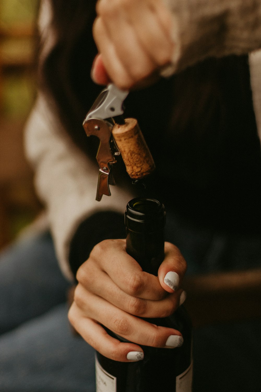 a woman holding a corkscrew and a bottle of wine