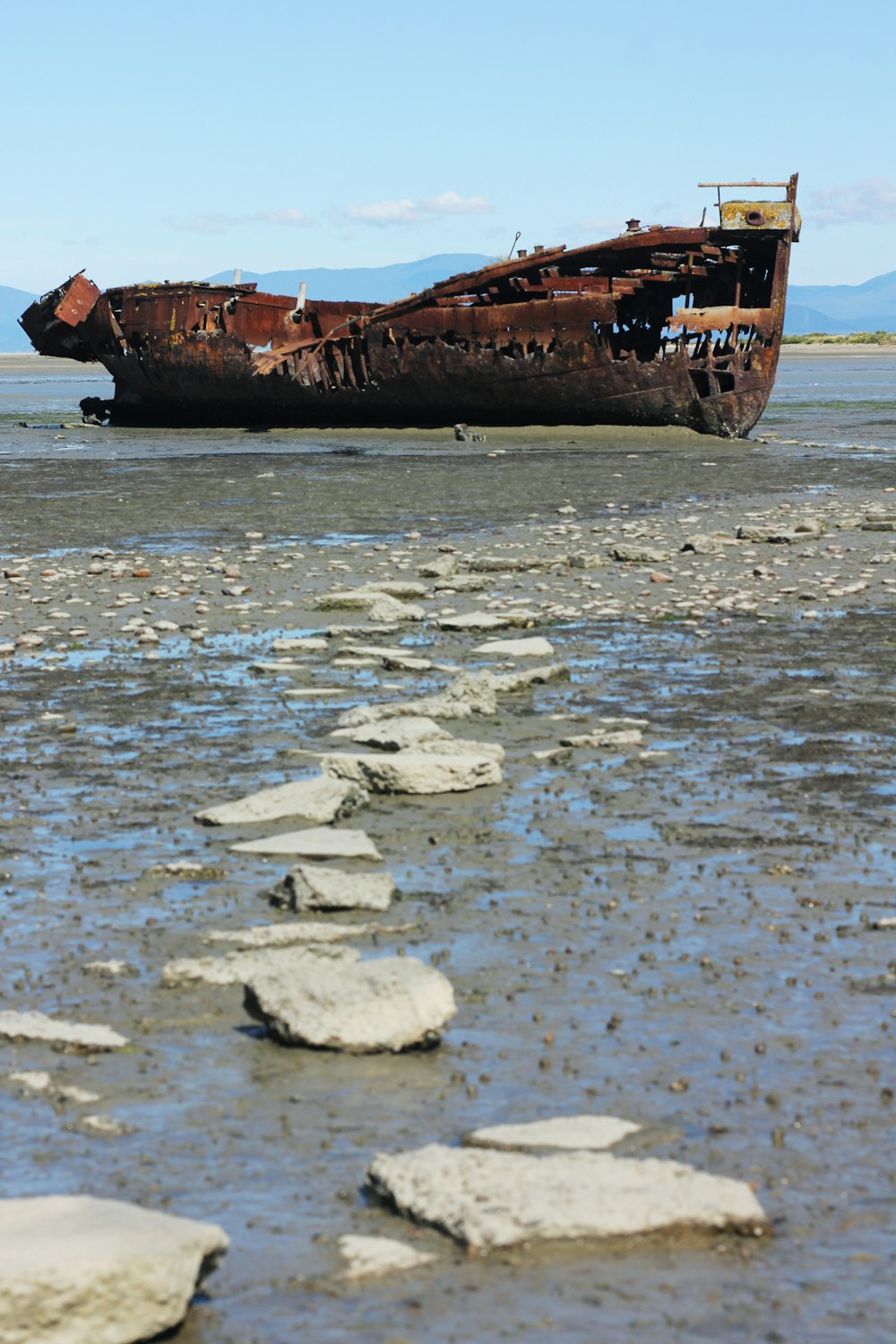 a rusty ship sitting on top of a body of water