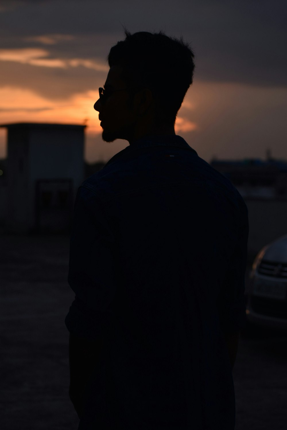 a man standing in a parking lot at sunset