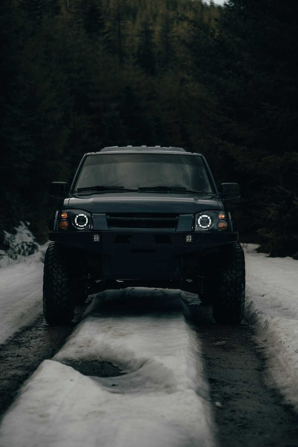 a black truck driving down a snow covered road