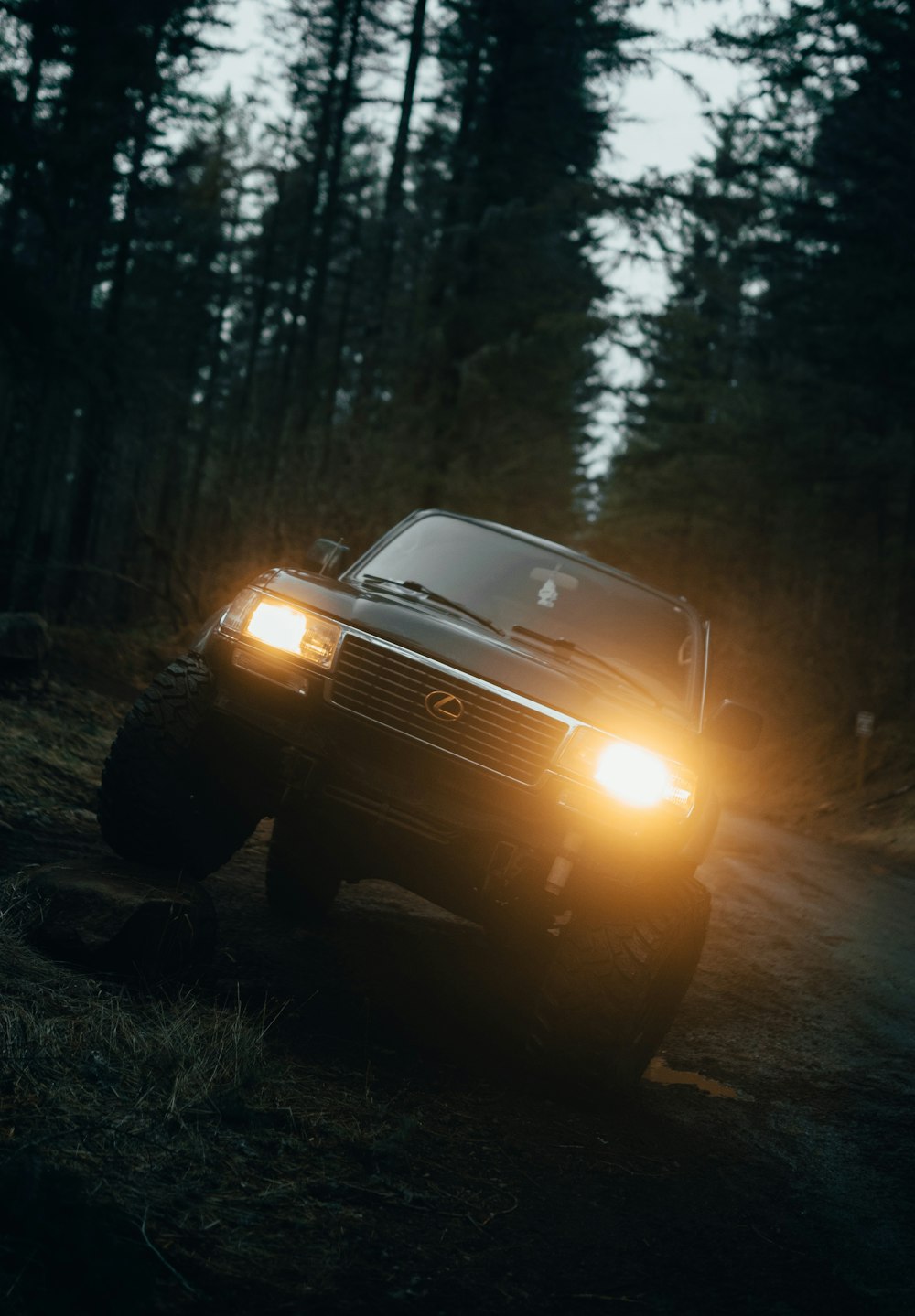 a truck with its headlights on driving down a road