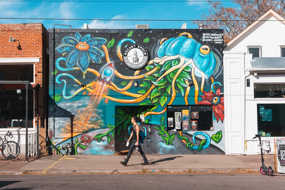 Una persona caminando junto a un edificio con un mural