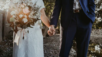 A couple holding hands with a musician playing guitar softly in the background during a wedding ceremony.