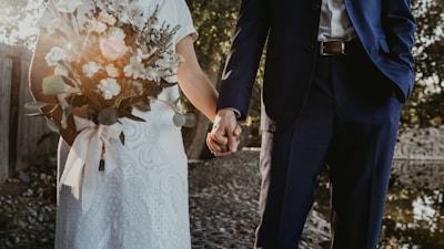 A joyful couple holding hands in a sunlit garden, ready for their wedding celebration