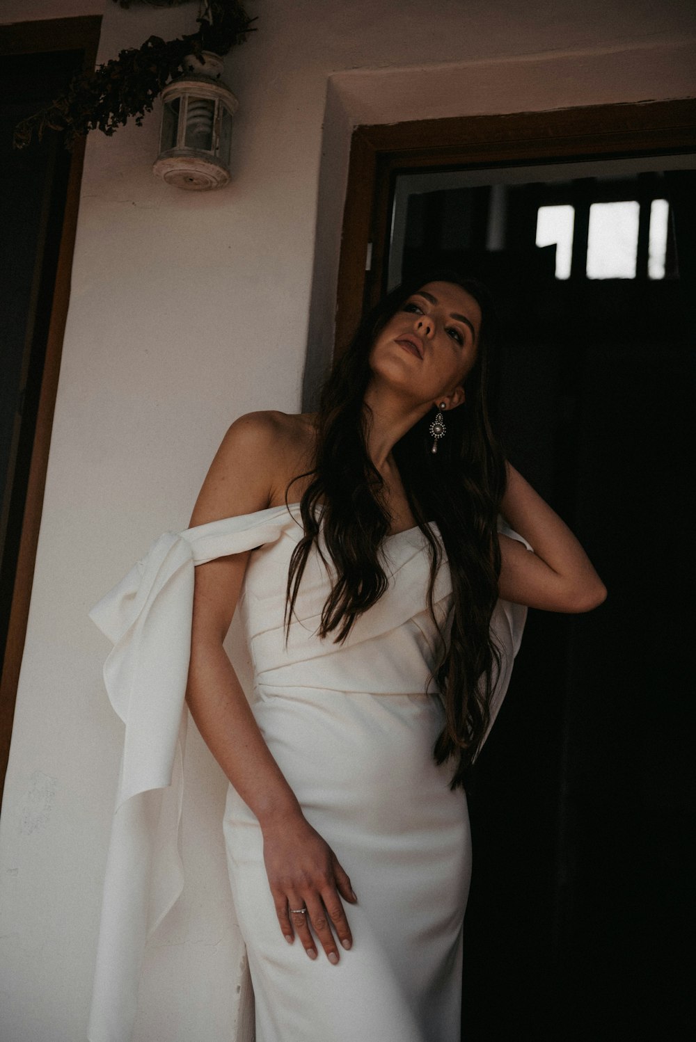 a woman in a white dress leaning against a wall