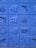 A series of blue blocks featuring various geometric shapes and patterns are displayed. The shapes include triangles, circles, arches, and lines carved into the blocks. The blocks are arranged in a grid pattern, creating a visually pleasing design with textured surfaces.