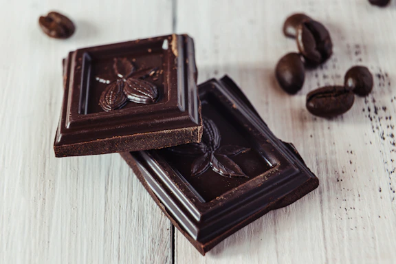Close-up of glossy dark chocolate vanilla beans arranged on rustic wood.